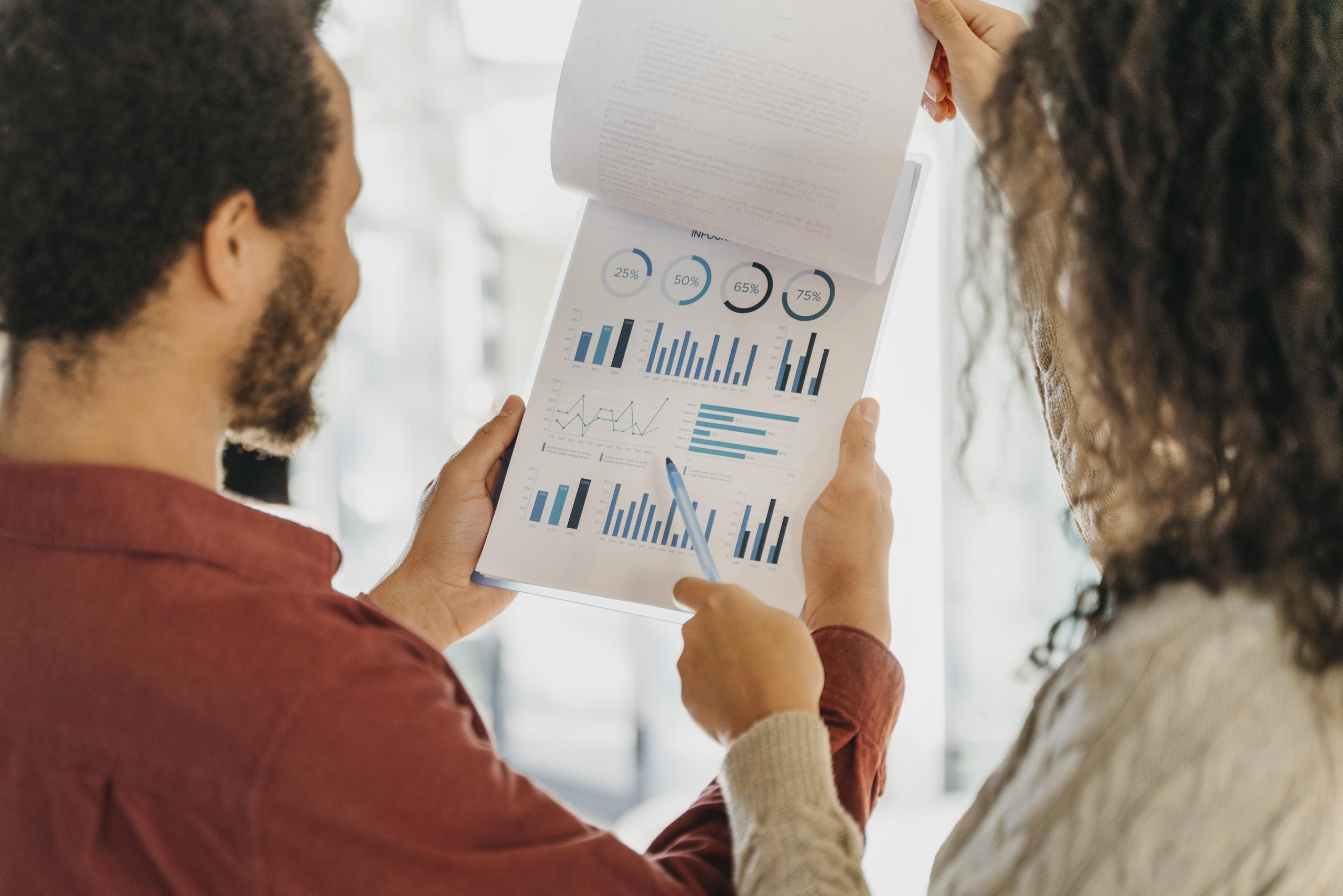 A man and a woman review a financial report featuring various charts and graphs, pointing at performance metrics—illustrating a detailed analysis session possibly involving investment decisions such as preference shares.